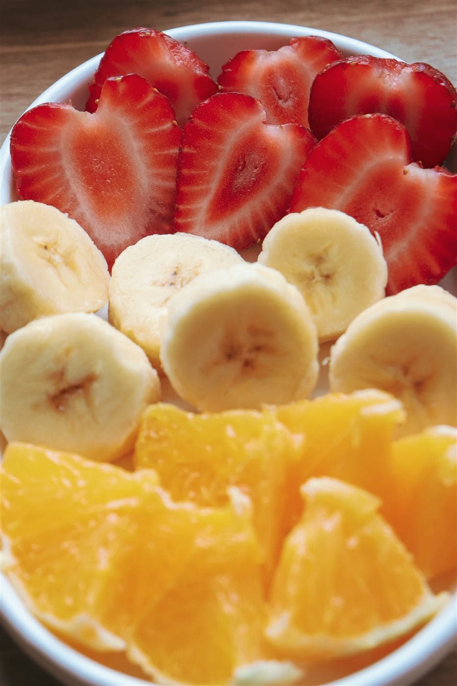 Tigela com salada de frutas frescas já fatiadas: morango, banana e laranja